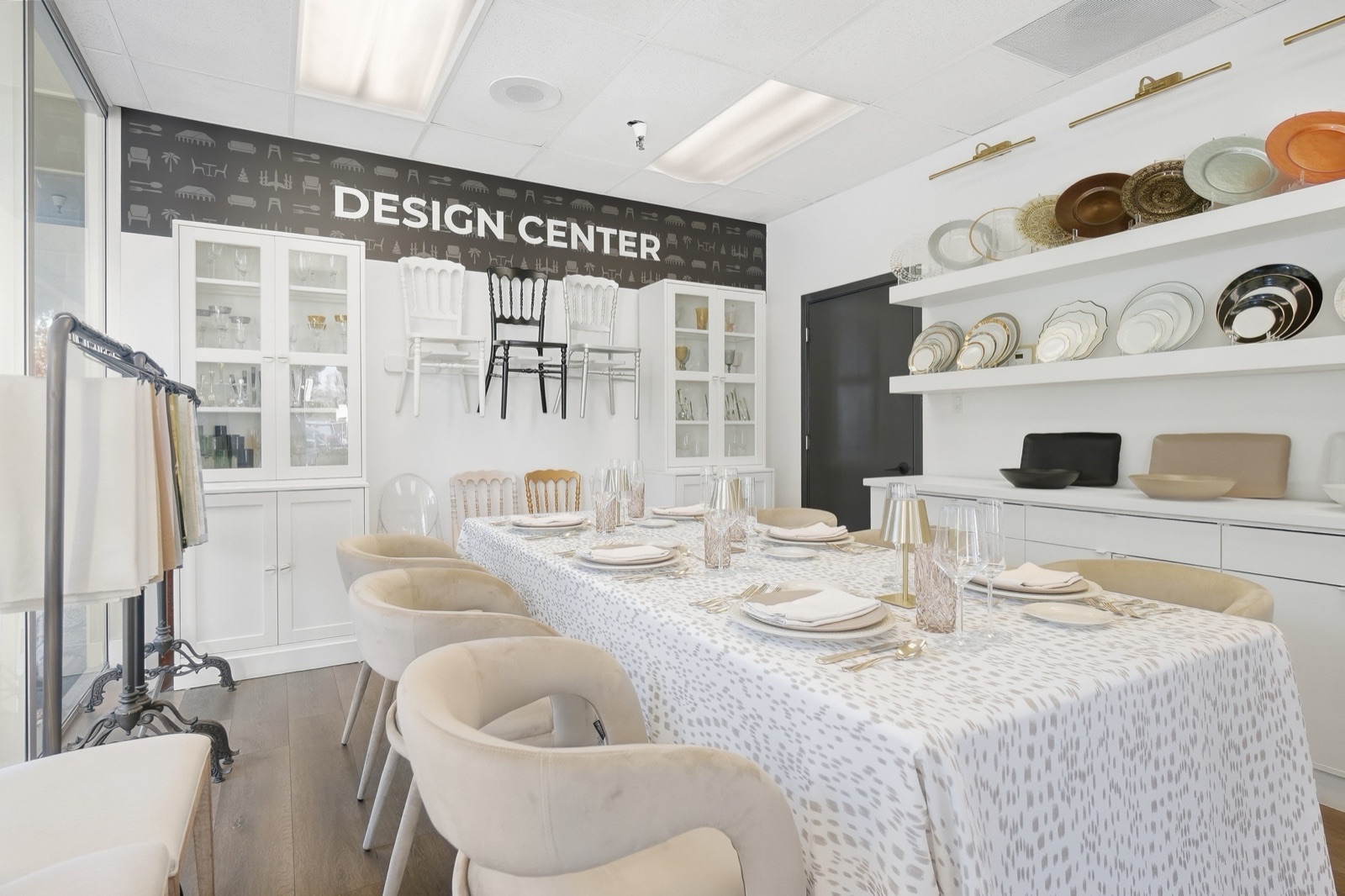 A long table set with patterned linens and place settings in the Design Center, with chairs and china displayed along the walls.